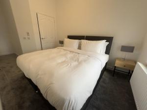 a large white bed with white sheets and pillows at Willowcrest in Airdrie +3 photos