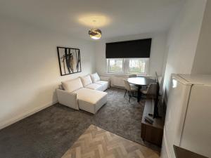 a living room with a white couch and a table at Lesmahagow Hilltop View in Lesmahagow