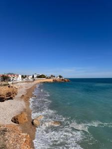 una playa con rocas y el océano en un día despejado en Apartment Tres Palmeras with pool, en Vinarós