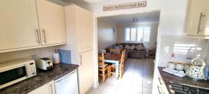 eine Küche und ein Wohnzimmer mit einem Tisch und einer Couch in der Unterkunft Ocean's Eddge, Perranporth in Perranporth + 11 Fotos