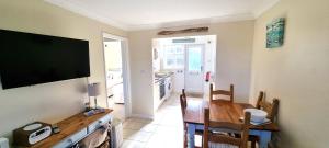 ein Esszimmer mit einem Tisch und einem Flachbildfernseher in der Unterkunft Ocean's Eddge, Perranporth in Perranporth