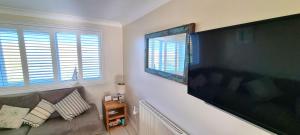 ein Wohnzimmer mit einem großen Flachbild-TV an der Wand in der Unterkunft Ocean's Eddge, Perranporth in Perranporth