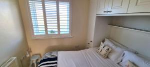 ein kleines Schlafzimmer mit einem Bett und einem Fenster in der Unterkunft Ocean's Eddge, Perranporth in Perranporth