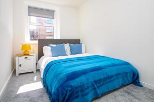 a bedroom with a bed with blue sheets and a window at 3-Bed Apartment - Near Clyde Shipyard - 25 min Glasgow Airport in Greenock