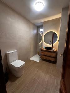 a bathroom with a toilet and a sink and a mirror at Duplex De los Reyes Católicos con parking incluido in Burgos