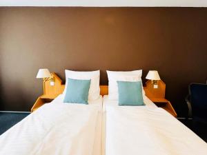 a large white bed with two blue pillows on it at Augustin Hotel und Restaurant Meersburg in Meersburg +1 photo