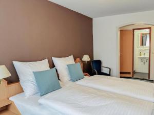 a bedroom with a large white bed with blue pillows at Augustin Hotel und Restaurant Meersburg in Meersburg