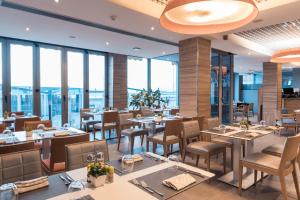 a restaurant with tables and chairs and large windows at Hotel Vague d'or in Staoueli