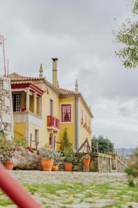 a yellow house with red windows and potted plants at Casa do Salgueiral in Santa Marta de Penaguião