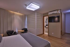 a bedroom with a bed and chairs and a television at Transamerica Lagoa Santa in Lagoa Santa