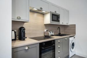 a kitchen with white cabinets and a sink and a microwave at Loch Lomond Retreat in Bonhill