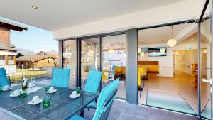 a patio with a table and blue chairs on a balcony at Villa am Achenweg in Saalfelden am Steinernen Meer