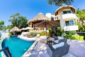 una casa con piscina con sillas y sombrilla en Casa Wapa Espectacular Villa Boho Chic en Acapulco, en Acapulco