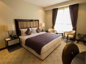 Una habitación de hotel con una cama grande y una mesa. en Premium Strato Hotel, en Doha
