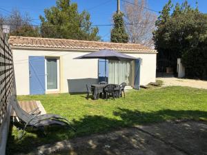 a table and chairs with an umbrella in a yard at Maison de vacances en campagne in Cavaillon