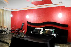 a bedroom with a bed and a red wall at Floresta Tucuruvi (Adult Only) in São Paulo