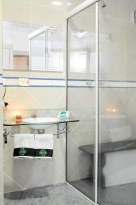 a bathroom with a glass shower and a sink at Floresta Tucuruvi (Adult Only) in Sao Paulo