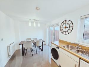 a kitchen with a table and a clock on the wall at Spacious 2 BEDROOM HOUSE in Dartford in Dartford