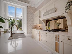 a white kitchen with a sink and a stove at Hallfield Hall in Alfreton