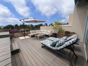 a patio with a couch and an umbrella on a deck at Très beau duplex avec Jacuzzi privatif in Mandelieu-La Napoule