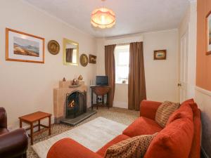 ein Wohnzimmer mit einem roten Sofa und einem Kamin in der Unterkunft Dalar Cottage in Brynkir