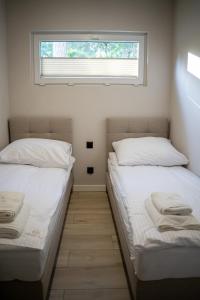 two beds in a small room with a window at Resort Hel domki letniskowe in Hel +16 photos