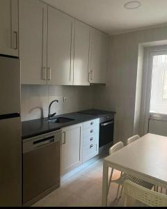 una cucina con armadi bianchi, tavolo e lavandino di Chalé do Tejo a Moita