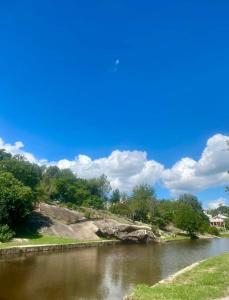 a river with trees and a blue sky with clouds at Happy House in Tanti