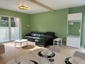 a living room with a leather couch and a table at Appartement NEUF, 6 personnes, 2 chambres in Ohligsmühle