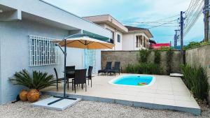 a patio with a table and an umbrella and a pool at Brusque: Casa aconchegante com piscina in Limeiro