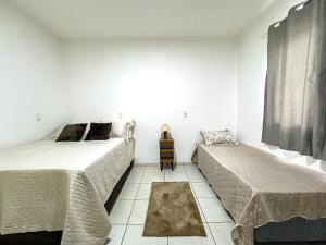 two beds in a room with white walls at Brusque: Casa aconchegante com piscina in Limeiro +24 photos