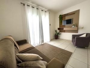 a living room with a couch and a chair and a television at Brusque: Casa aconchegante com piscina in Limeiro