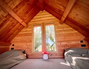 1 dormitorio con 2 camas y una ventana en una cabaña de madera en Cabane La Fontaine du Figuier, en Saint-Maurice-sur-Eygues