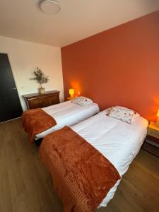 two beds in a room with orange walls at Eden Forest & Spa in Saint-Amand-les-Eaux