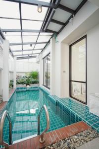 an indoor swimming pool with blue tile in a building at Somewhere house in Bangkok