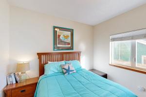 a bedroom with a bed with a blue comforter and a window at Ninos Al Mar in Rockaway Beach