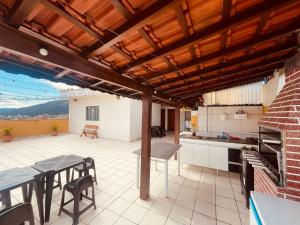 a patio with a table and chairs and a kitchen at Apto Cobertura Santa Rosalia in Poços de Caldas