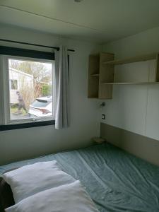 ein Schlafzimmer mit einem Bett vor einem Fenster in der Unterkunft Mobil home in Talmont
