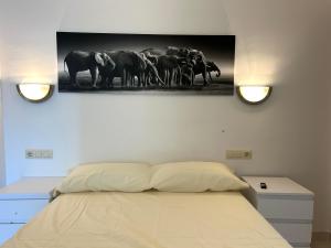a bedroom with a bed and a painting of a herd of elephants at Apartamentomagy in Carboneras