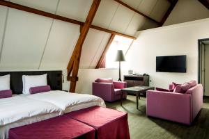 a bedroom with a bed and two chairs and a tv at Hampshire Hotel - 's Gravenhof Zutphen in Zutphen