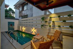 a balcony with a pool and chairs and a table at Villa Savaaya Assagao Goa in Assagao