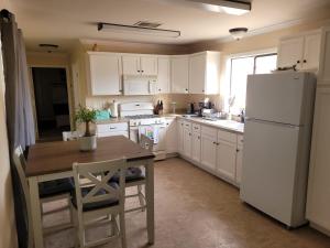 a kitchen with a table and a white refrigerator at Alpaca Rustic Ranch-peaceful & breathtaking views in Santa Clarita