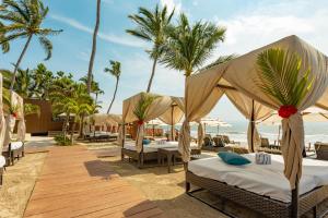 a resort with beds on the beach with palm trees at Marival Emotions Resort & Suites Riviera Nayarit by Mercure in Nuevo Vallarta