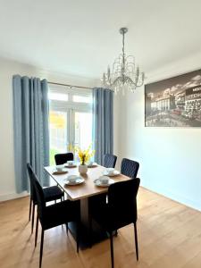a dining room table with chairs and a chandelier at Luxury House in Ilford 21 minute Train journey from Central London in Ilford