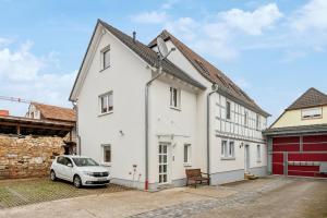 a white house with a car parked in the driveway at 2 BR Apartment mit Parkplatz in Haßloch
