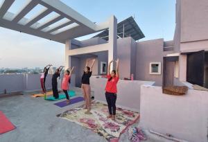 a group of people doing yoga on the roof of a house at Yoga Retreat Wellness by Atulyam in Lucknow