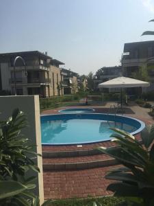 a large swimming pool with an umbrella and some buildings at D-S Apartman Stella in Zamárdi