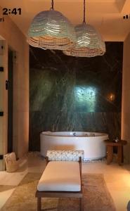 a bathroom with a bath tub and a bench and two chandeliers at Vidanta Nuevo Vallarta in Nuevo Vallarta 