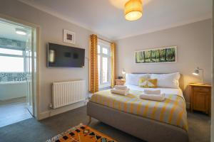 a bedroom with a bed and a tv on the wall at Vibrant 2 Bed, 2 Bath Home, Just Minutes to Town! in Ross on Wye