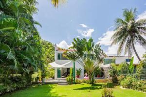 a white house with palm trees and a yard at Lux 4BR Playacar Villa with Pool in Playa del Carmen
